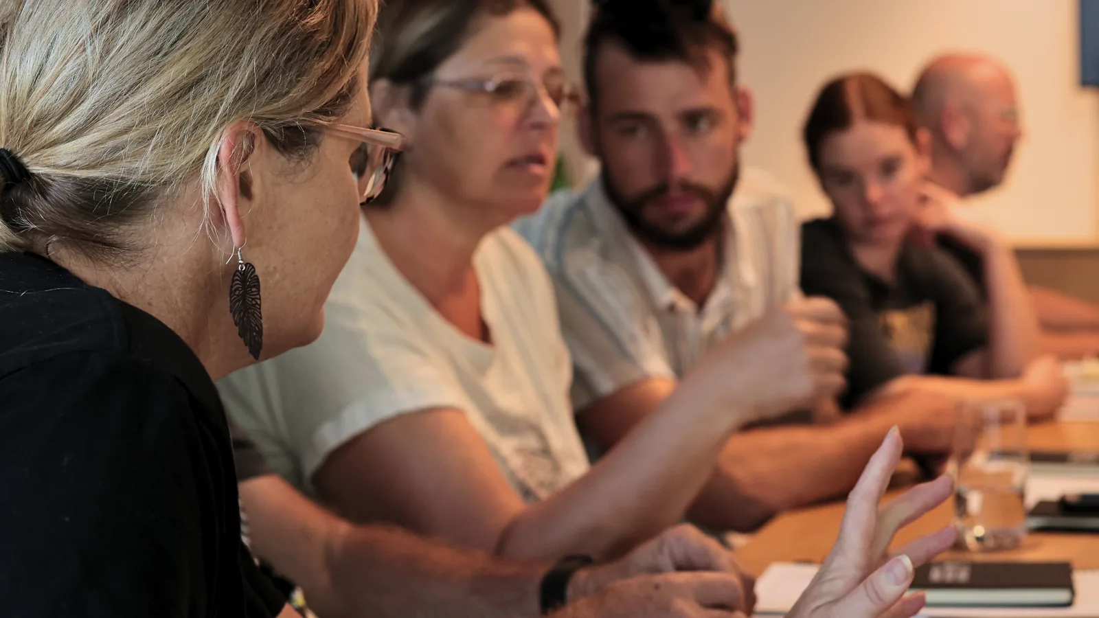 Five trade business owners along one side of a table, one gesturing while the others listen