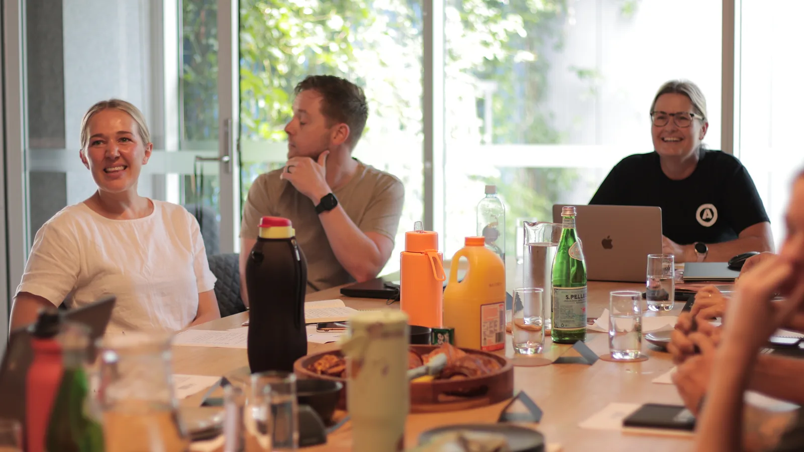 Five trade business owners around a table over food and notebooks, big window behind them