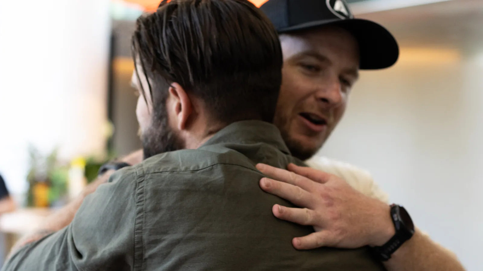 Two trade business owners in an embrace at an Academy event, one of them in a Tradies Success Academy cap