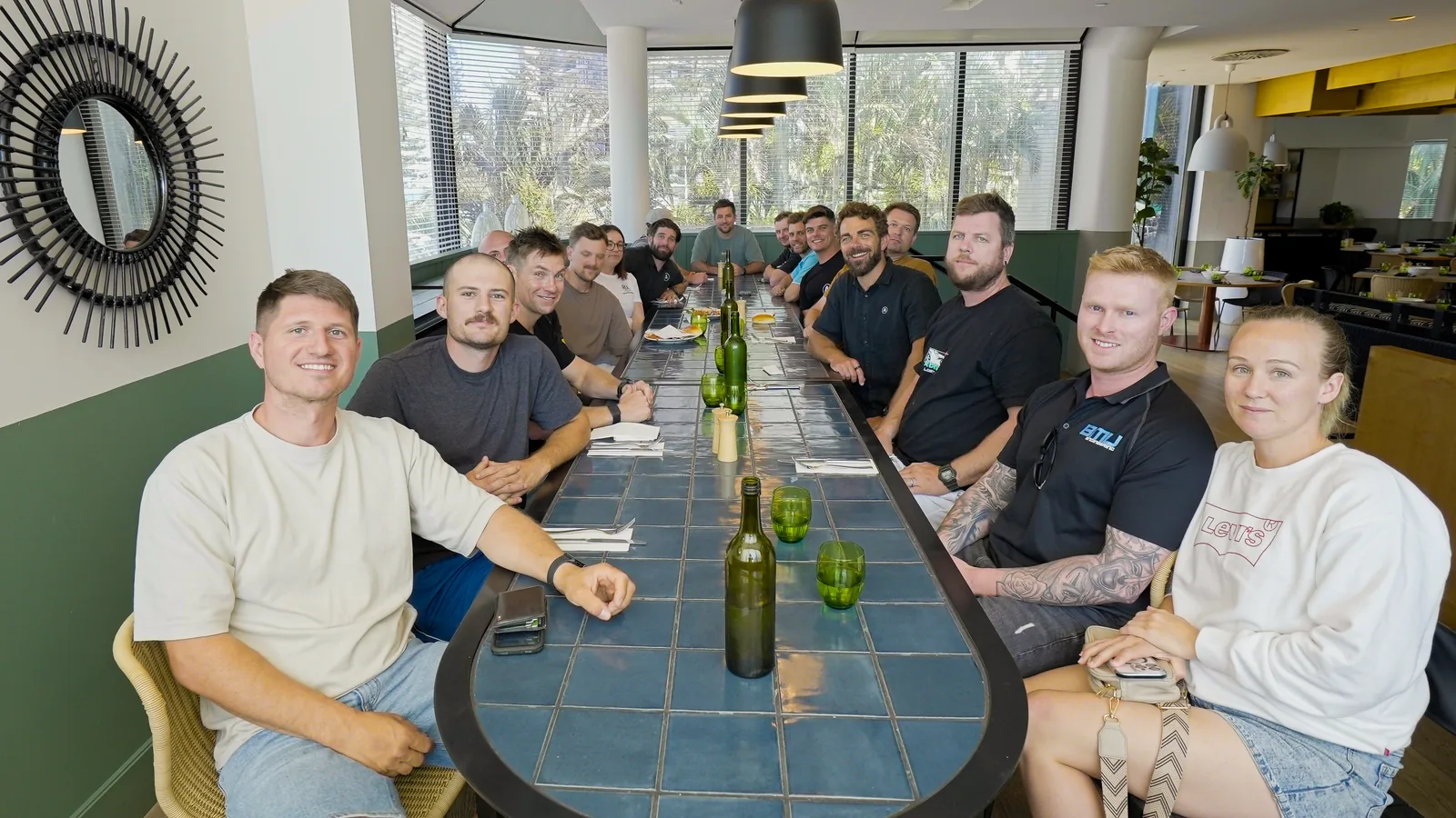 Fourteen trade business owners along a long table at an Academy event, looking to camera